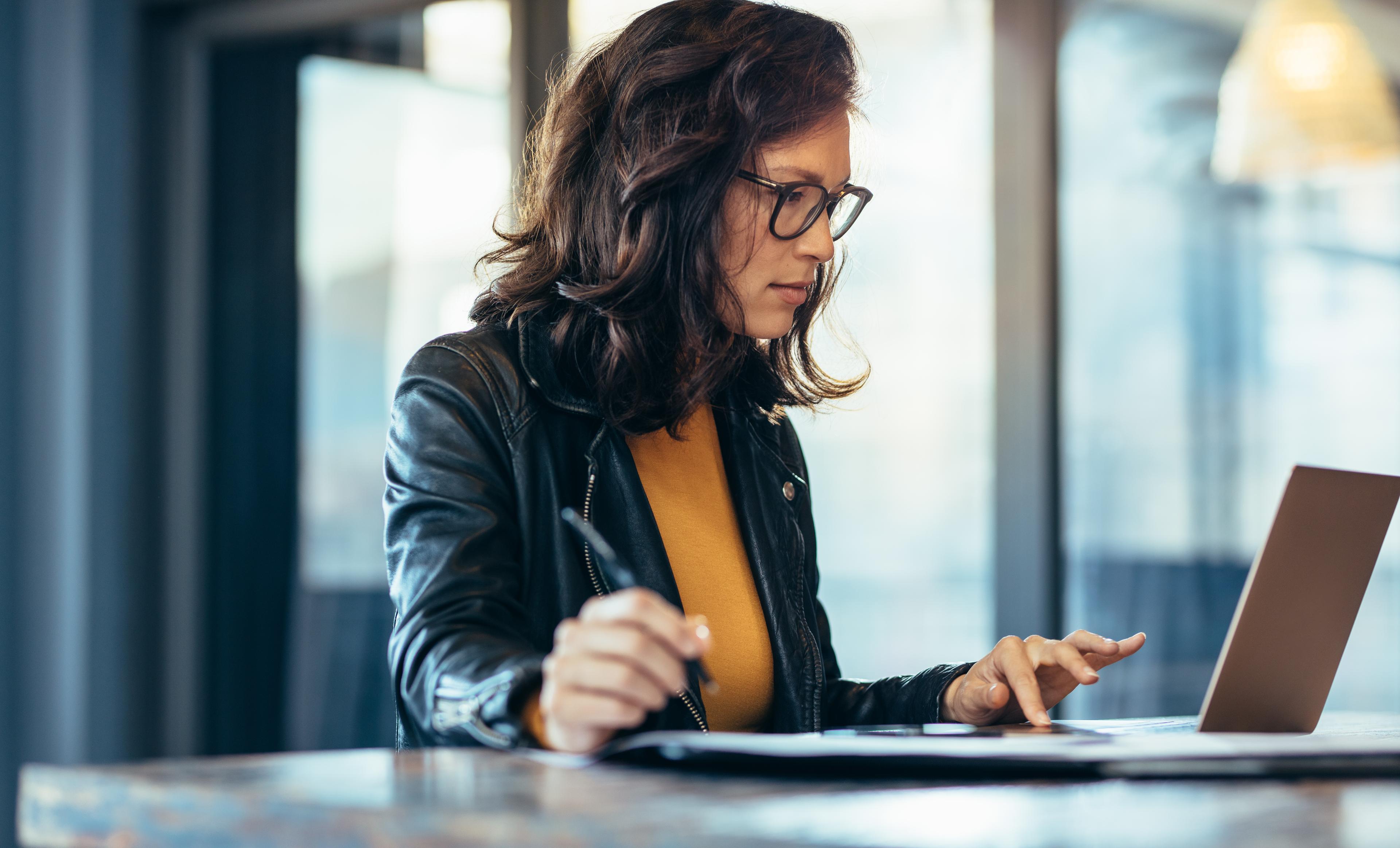 woman using a computer and a pen in hand